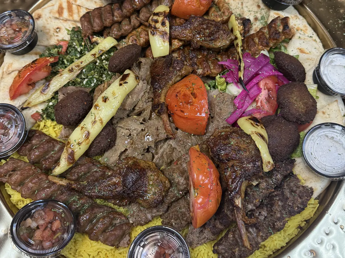 The Family Platter at Kaboblicious: lamb kabobs, Adana chicken and beef kabobs, lamb chops, shaved lamb gyro and falafel over rice on a large brass tray, with mixed salad, pita and white sauce